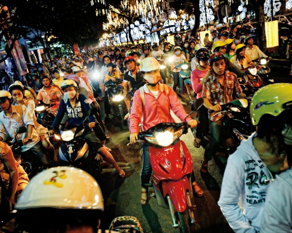 Motorbike traffic filling a brightly lit street in Ho Chi Minh City