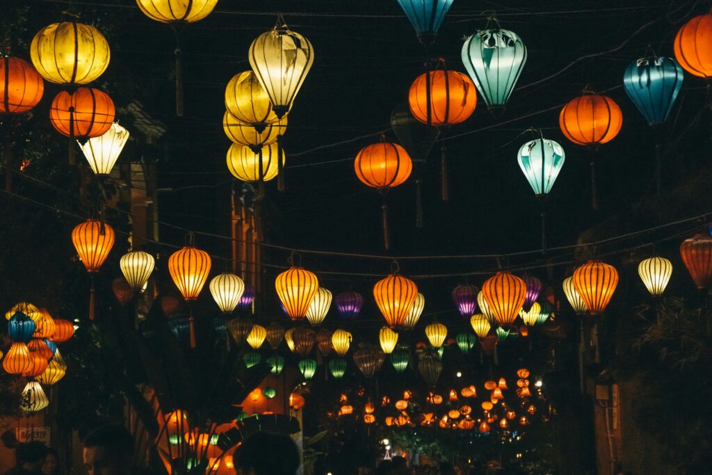 Colourful lanterns glowing above a street in Hoi An at night