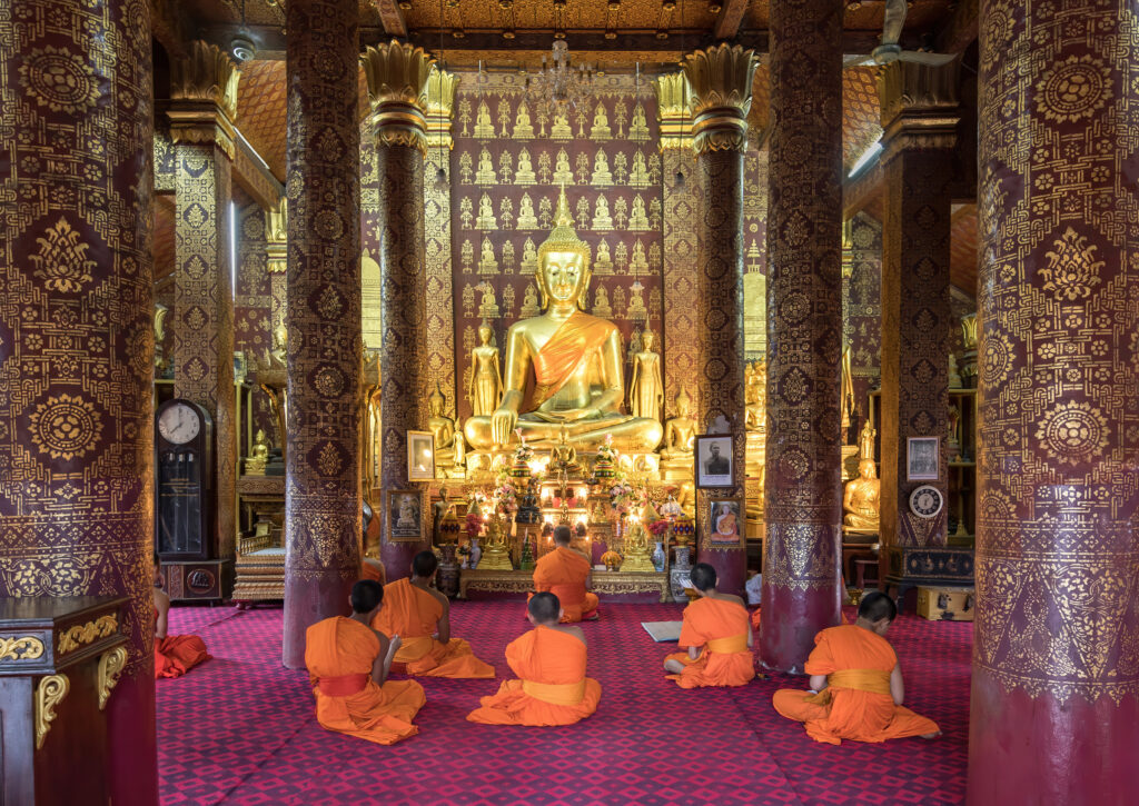 Praying bhikkhus inside Wat Sensoukharam in Luang Prabang Laos