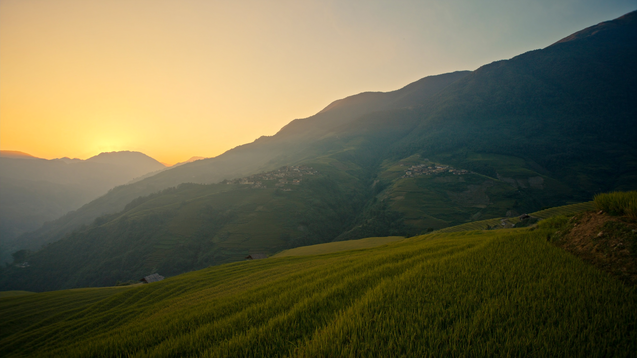 Sunrise over stepped rice terraces and a mountain village in Hoang Su Phi