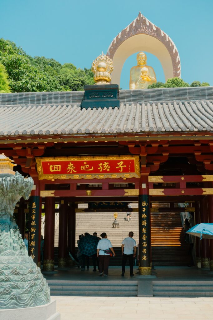 Rock-cut grotto temple with golden Buddha in sunlit exterior setting